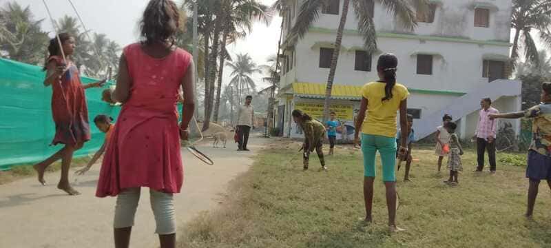 Schülerinnen in Indien spielen zusammen Springseil und Federball.